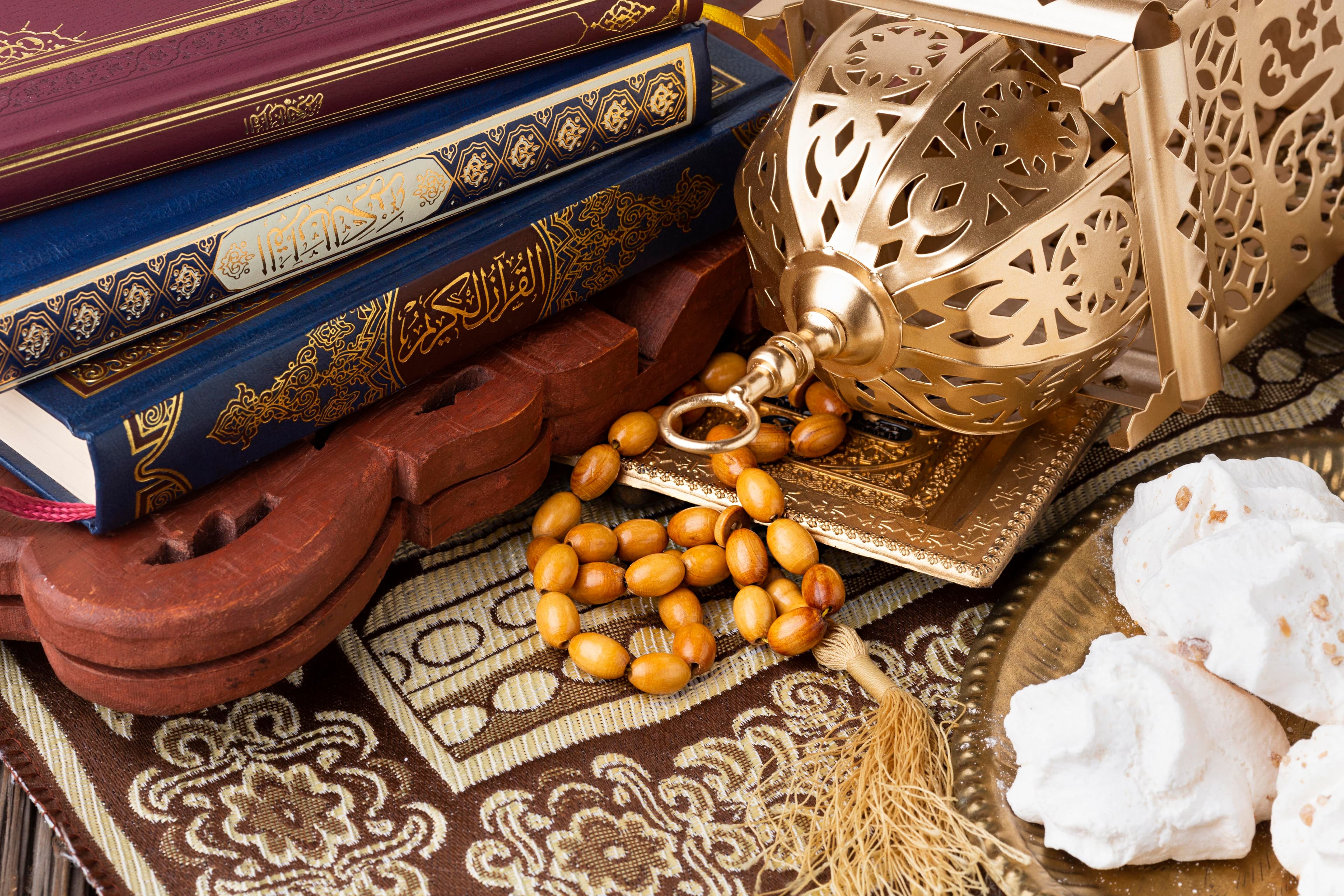 Qur'an, lantern, prayer beads, and learning materials on a patterned rug